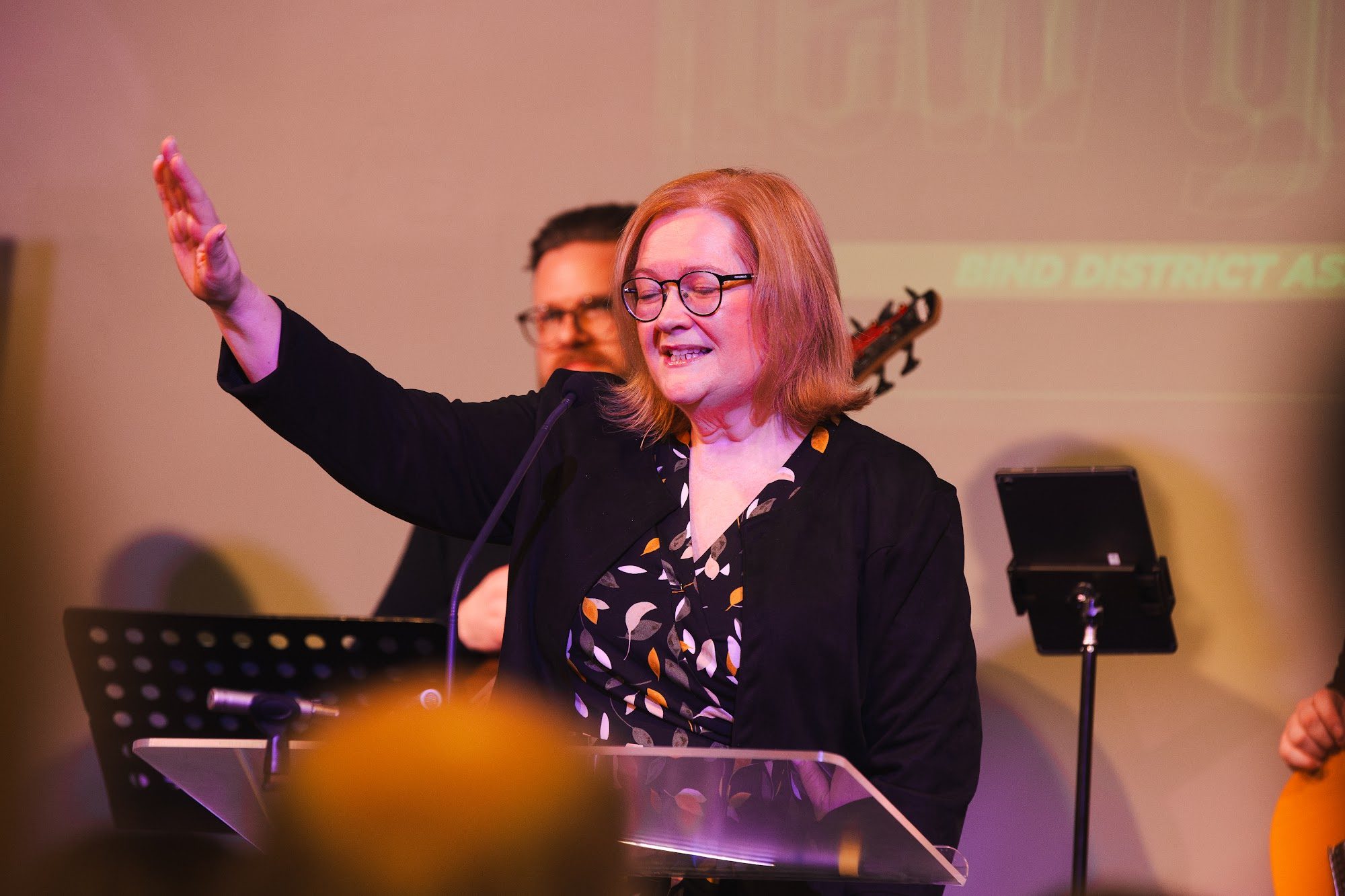 A woman leading prayer with her hand raised