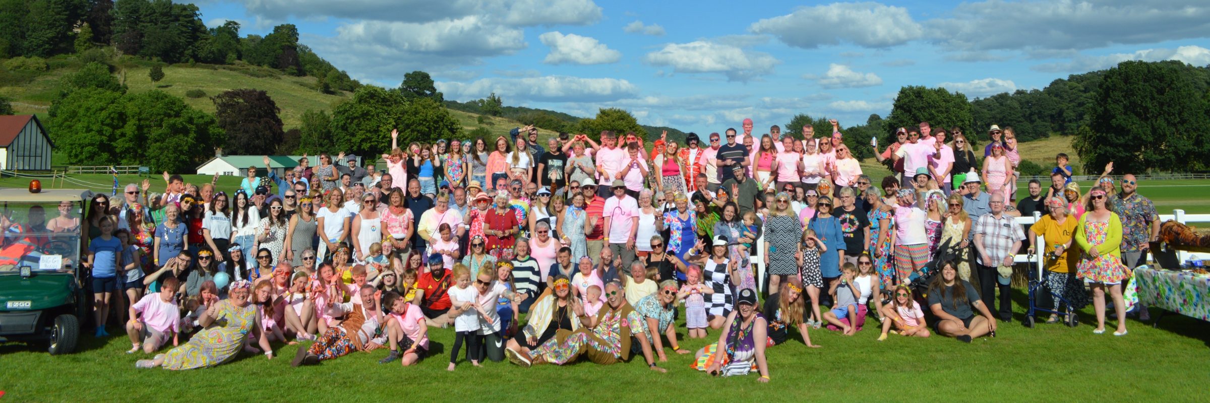 A large group of Northbreak guests gathered on a lawn with green hills behind